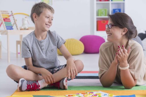 Jongen en behandelaar op de grond min min